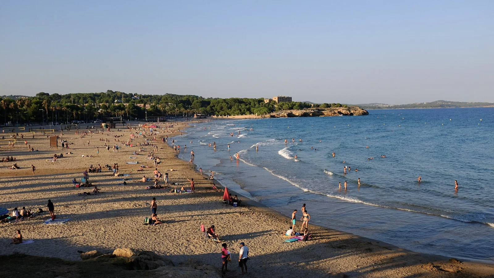 La platja de l'Arrabassada, a Tarragona, amb gent a la sorra i onades que arriben a la vora.